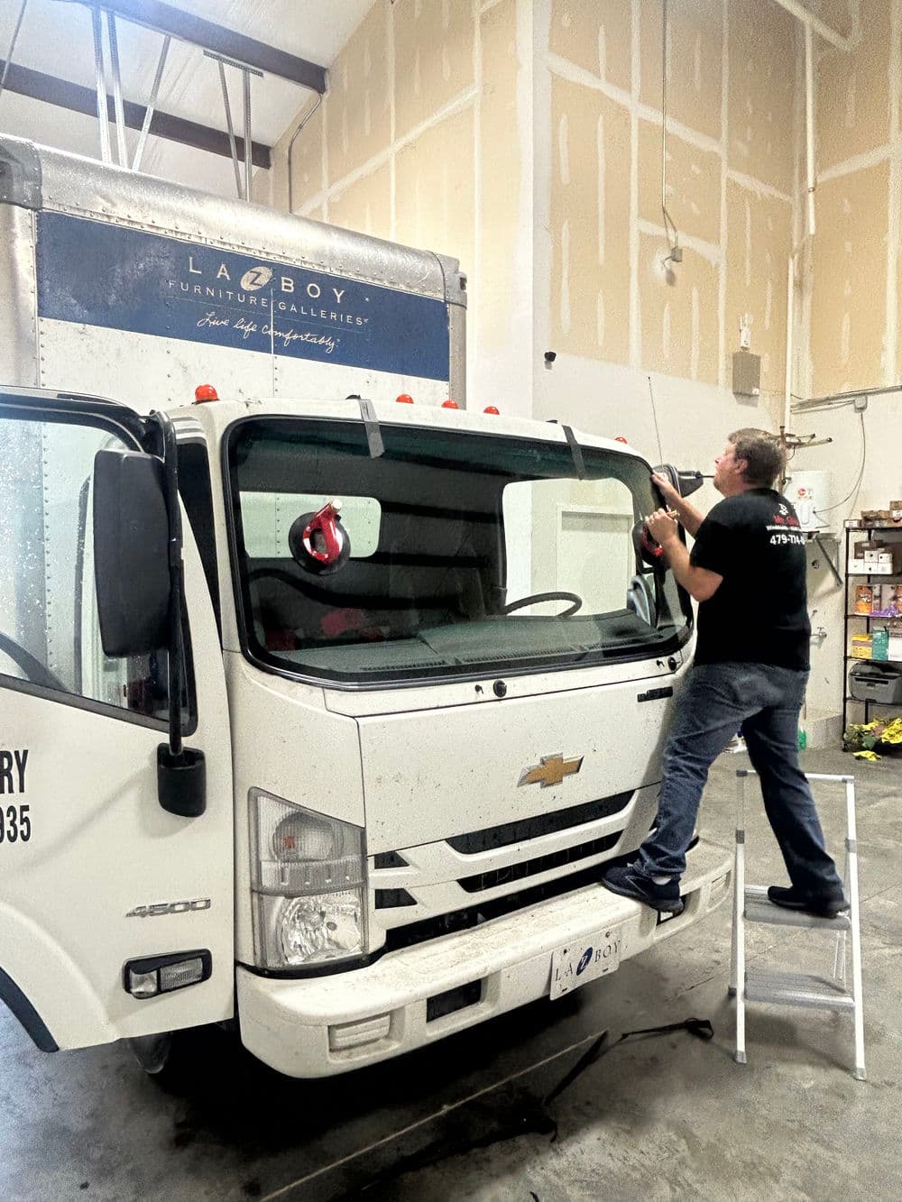 Person cleaning the windshield of a delivery truck inside a warehouse.