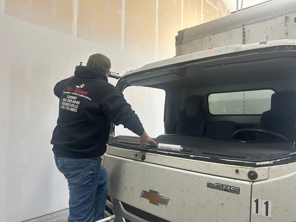 Technician replacing windshield on Chevrolet truck at Mr. Glass automotive workshop.